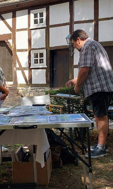 Der Kunstlehrer arbeitet während der Aktion „Malen um die Burg 2025“ im Innenhof der Burg Dringenberg, umgeben von ausgestellten Kunstwerken.